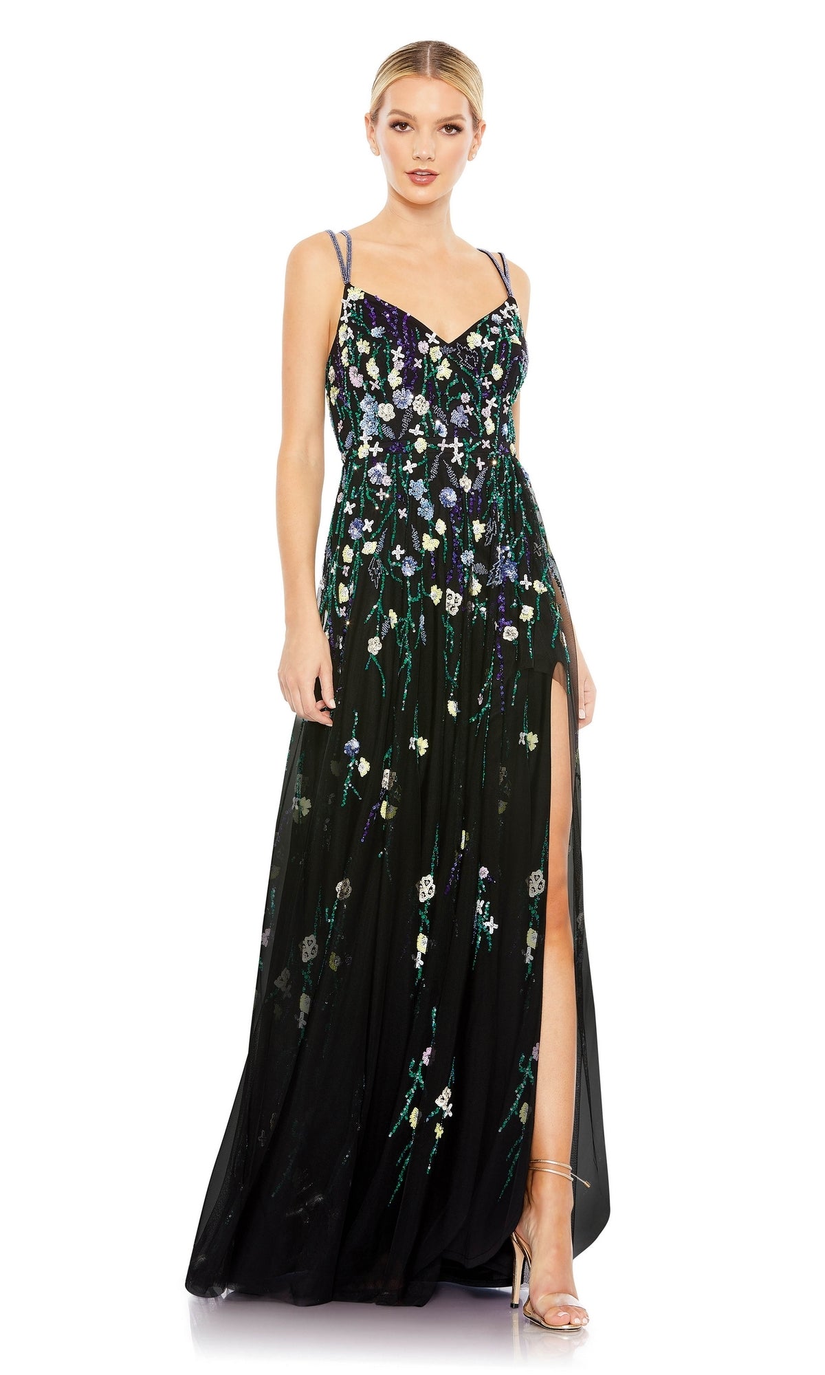 A woman wears the Floral-Sequin Long Black Formal Dress 9172 by Mac Duggal, featuring colorful floral embroidery, sequin flowers, thin straps, a sweetheart neckline, and a thigh-high slit, styled with strappy heels.